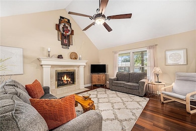 Living area with high vaulted ceiling, dark wood finished floors, a premium fireplace, and a ceiling fan