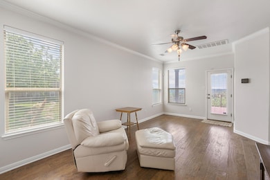 Sitting room featuring a ceiling fan, baseboards, wood finished floors, and crown molding