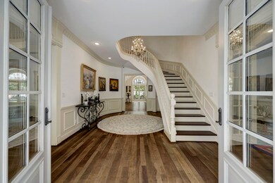 The center hall with sweeping staircase welcomes,