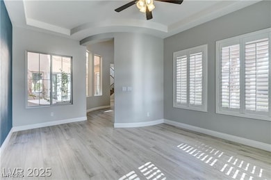 Empty room featuring ceiling fan, arched walkways,