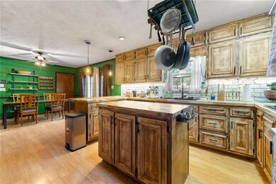 Large Kitchen featuring butcher block counters, a kitchen island, light laminate wood-type flooring