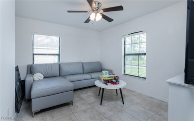 Living room with ceiling fan and light tile patter