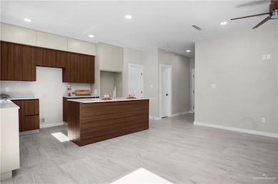 Kitchen featuring recessed lighting, modern cabinets, a kitchen island, ceiling fan, and light stone countertops