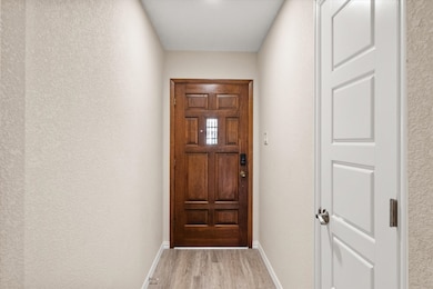 Doorway to outside featuring wood finished floors and a textured wall