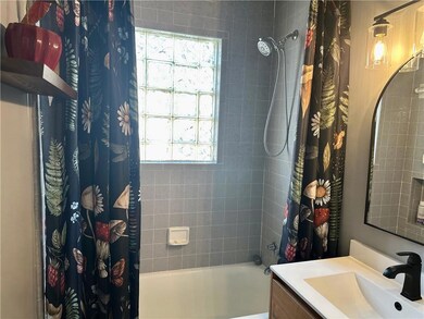 Full bath with shower / tub combo with curtain, vanity, and plenty of natural light