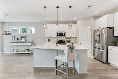 Kitchen featuring stainless steel appliances, light quartz countertops, decorative backsplash, a kitchen island with sink, and upgraded white cabinets with soft close drawers and doors