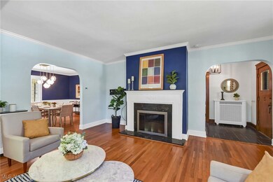 Living room with a high end fireplace, dark hardwood / wood-style flooring, a notable chandelier, radiator, and ornamental molding