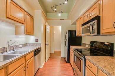 Kitchen with appliances with stainless steel finishes, light wood-style floors, and light countertops