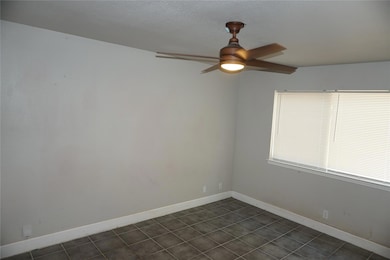 Unfurnished room featuring dark tile patterned floors and a ceiling fan