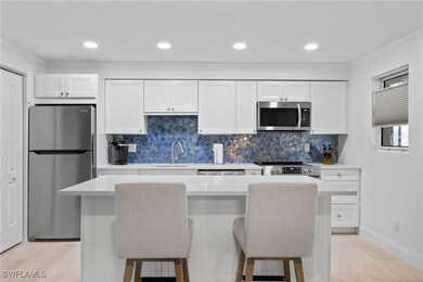 Kitchen featuring backsplash, white cabinets, stainless steel appliances, a breakfast bar, and a kitchen island