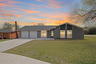 Mid-century home featuring a yard, a garage, and 
