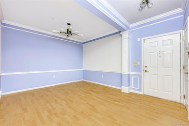 Entryway & Formal Dining Room featuring ornamental molding, decorative columns, light wood-type flooring, and a ceiling fan
