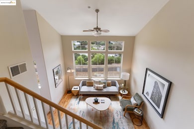 Living room with wood finished floors, a ceiling fan, and a towering ceiling