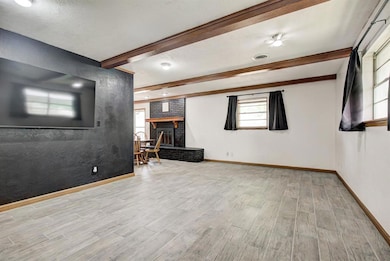 Unfurnished living room featuring beam ceiling, a fireplace, and light wood finished floors