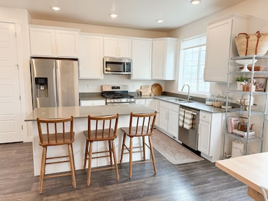 Kitchen featuring a kitchen breakfast bar, stainless steel appliances, white cabinets, a kitchen island, and recessed lighting