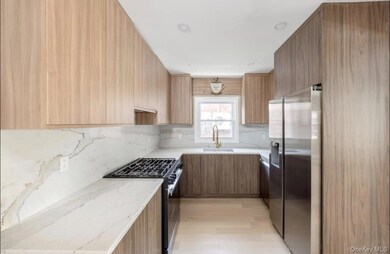 Kitchen with modern cabinets, appliances with stainless steel finishes, and light stone counters