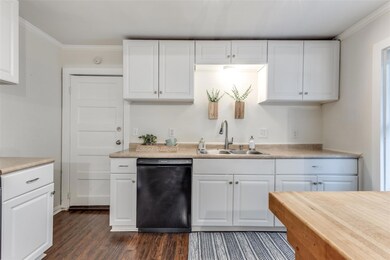 Kitchen with sink, white cabinetry, dark wood-type