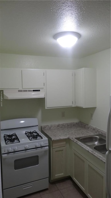 Kitchen featuring a textured ceiling, a sink, ligh