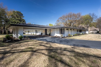 Ranch-style home with brick siding, an attached carport, asphalt driveway, and a front lawn