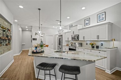Kitchen featuring appliances with stainless steel finishes, a breakfast bar area, decorative backsplash, white cabinets, and light wood-style floors