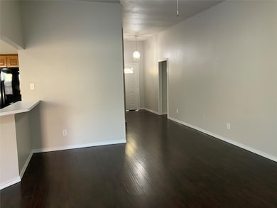Spare room featuring dark wood-style flooring and baseboards