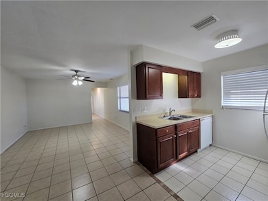 Kitchen with light tile patterned flooring, light countertops, ceiling fan, dishwasher, and dark brown cabinets