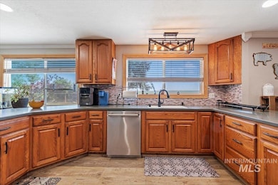 Kitchen featuring stainless steel dishwasher, light wood-style flooring, brown cabinetry, plenty of natural light, and a textured ceiling