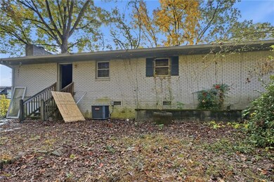 Back of house featuring brick siding, a chimney, crawl space, and stairs