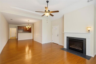 Unfurnished living room with a chandelier, dark wood-style flooring, a fireplace with flush hearth, and ceiling fan