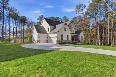 View of front of property with a front lawn, stone siding, concrete driveway, a shingled roof, and board and batten siding