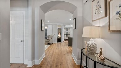 Hall with light wood-style flooring, arched walkwa