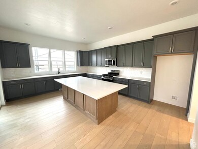Kitchen with backsplash, a kitchen island, appliances with stainless steel finishes, light stone countertops, and recessed lighting