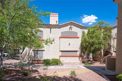 Rear view of property with stucco siding, a tile roof, a chimney, and stairs