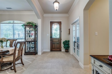 Entryway featuring a healthy amount of sunlight, crown molding, and light tile flooring