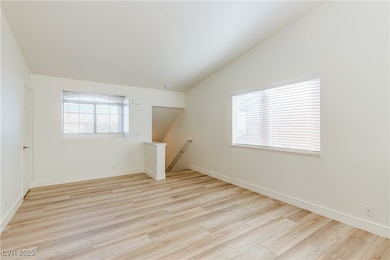 Unfurnished room featuring baseboards, vaulted cei