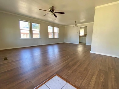Unfurnished living room with ornamental molding, dark wood finished floors, and ceiling fan