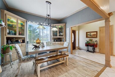 Dining space with decorative columns, light wood-type flooring, lofted ceiling, and ornamental molding