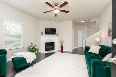 Living room featuring dark wood-type flooring, ceiling fan, and a premium fireplace