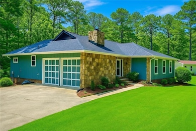 Single story home with a chimney, roof with shingles, a front yard, stone siding, and concrete driveway