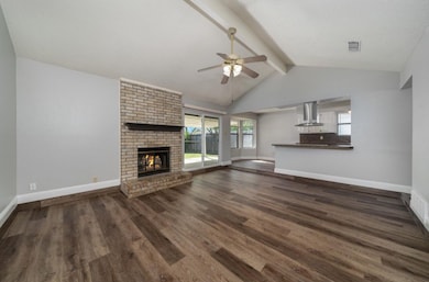 Unfurnished living room featuring a brick fireplace, dark wood-style floors, and a ceiling fan