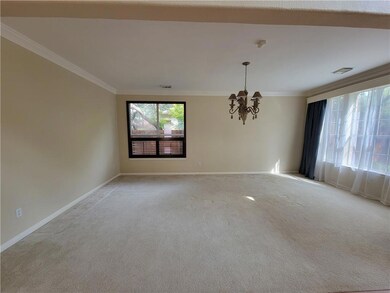 Empty room with a chandelier, light colored carpe