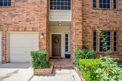 A classic covered entry framed by brick and greene