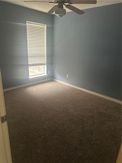 Carpeted spare room with ceiling fan and baseboard