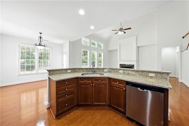 Kitchen with stainless steel dishwasher, a sink, wood finished floors, plenty of natural light, and recessed lighting