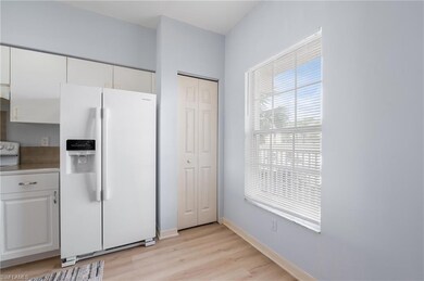Kitchen with white appliances, white cabinets, light countertops, and light wood-type flooring