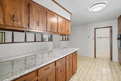 Kitchen with brown cabinets, light stone counters, and oven