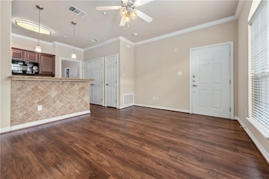 Unfurnished living room featuring ornamental molding, dark wood-type flooring, and ceiling fan