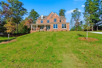 View of front facade featuring covered porch, a front yard, and brick siding