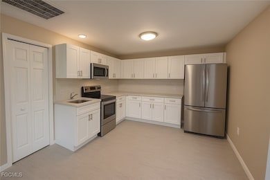 Kitchen with stainless steel appliances, tasteful backsplash, white cabinetry, and recessed lighting