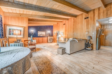 Living area featuring wooden walls, hardwood / wood-style flooring, and wood ceiling with exposed beams